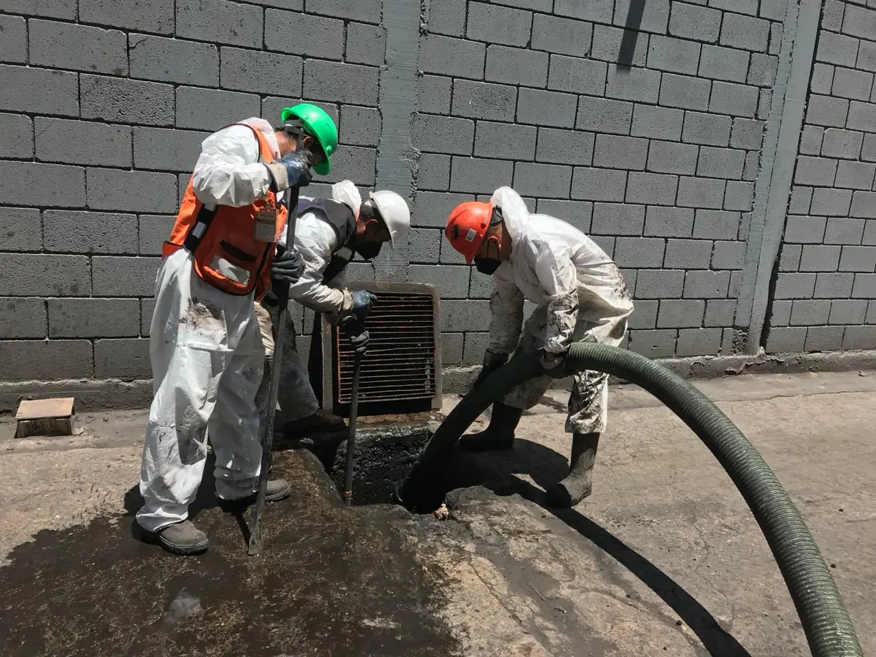 Extracción de residuos de un registro con equipo de protección completo